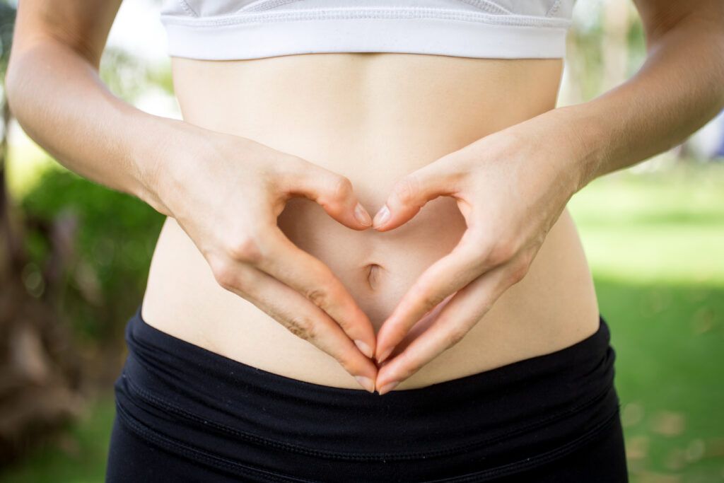 Close up of female hands shaping heart on belly